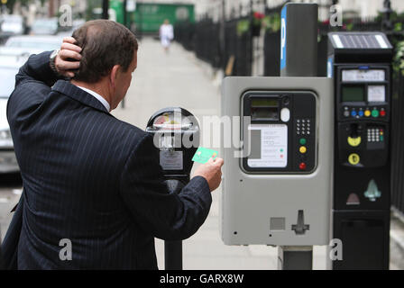 A man looks at three different parking meters, (left to right) a 1958 Duncan Single Space Meter, a Parkeon DG4 and a Strada Rapide parking meter, which form part of an array of historical parking meters on show in Grosvenor Square, London. Stock Photo