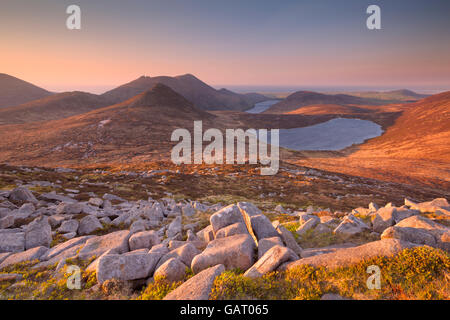 Sunrise over the Mourne Mountains and lakes in Northern Ireland. Photographed from the peak of Slieve Loughshannagh.