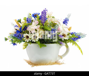 Table floral arrangement made of artificial flowers and cottons balls in stylized ceramic vase in form of tea cup isolated on wh Stock Photo