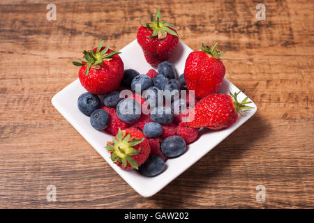 strawberries, raspberries and blueberries in a white bowl Stock Photo