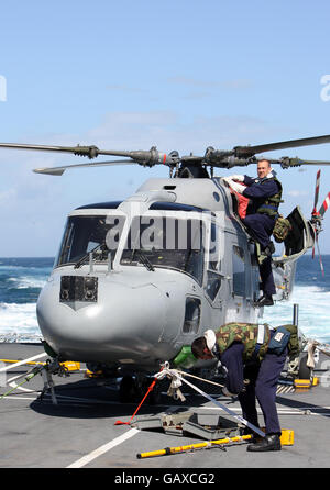 Royal Navy engineers working on a Lynx helicopter onboard HMS Cumberland. Stock Photo