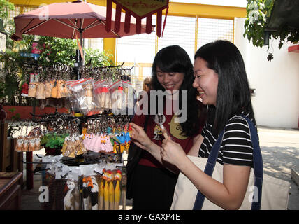 Two young Chinese women smile as they look at souvenirs in a shop at the Stanley Market. Stanley Village, Hong Kong. 06.05.2016. Stock Photo