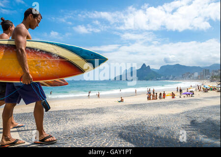 RIO DE JANEIRO - APRIL 3, 2016: Young carioca Brazilian couple walks with surfboards Arpoador, the popular surf point. Stock Photo