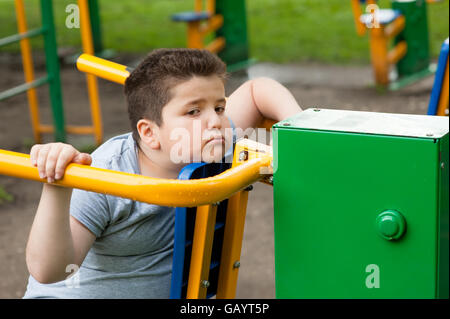 tired sad fat boy sitting on the sports simulator Stock Photo