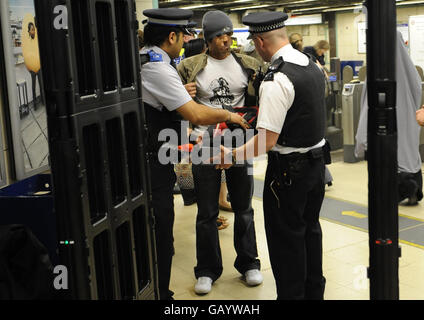 PASSENGER FACE HAS BEEN PIXELATED BY PA PICTURE DESK ON ADVICE FROM METROPOLITAN POLICE Police officers search commuters for knives with the aid of a metal detector as they pass through Mile End tube station in London. Stock Photo