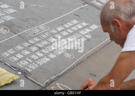 Street artist writing poems in chalk at Trafalgar Square, London in July Stock Photo