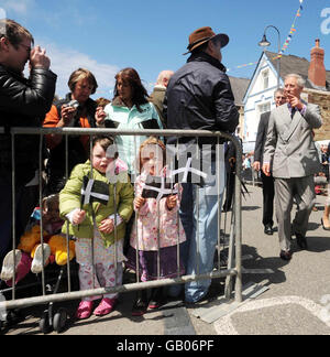 Lucy Haynes (left), 3, and Hannah Slade, 3, both from Tintagel, wave flags during The Prince of Wales (right) and the Duchess of Cornwall's (not shown) visit to The Old Post Office in Tintagel. The Prince and Duchess started their two day visit to Cornwall today. Stock Photo