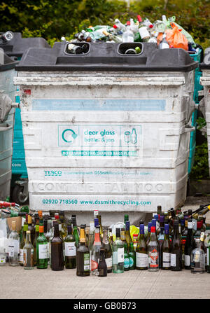 Overflowing recycling glass bottle bank in Winchester, UK with rows of wine bottles lined up in front Stock Photo