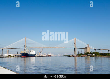 Freight industry at busy harbor on the Savannah River with suspension bridge Stock Photo