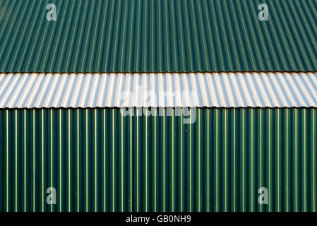Green and white corrugated metal surface of a wall and roof with vertical lines Stock Photo