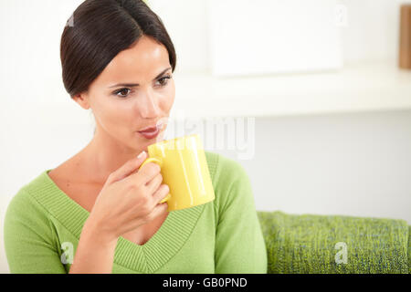 Young woman blowing into a hot coffee cup while looking away - copy space Stock Photo