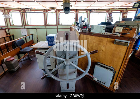 Helm steering wheel in the navigation room of a freight ship Stock Photo