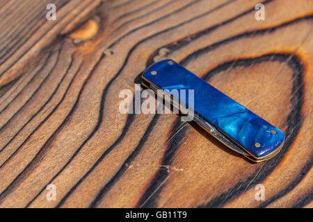 One multi-purpose or pocket knife lying on wooden table Stock Photo