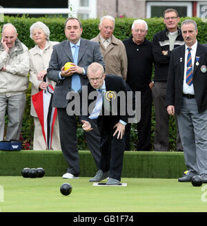 First Minister Alex Salmond waits for his shot while SNP candidate for Glasgow East, John Mason, plays a shot during a game of bowls while visiting Garrowhill Bowling Club, to highlight support for pensioners in the citys east end. Stock Photo