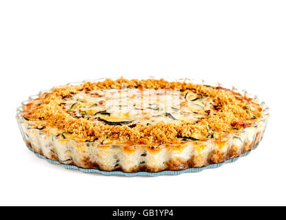 Lateral view of homemade crustless zucchini quiche baked in a glass fluted dish isolated on white Stock Photo