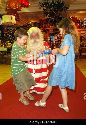 Father Christmas launches Christmas World with with Gabriella Emery, aged 7 and her brother Luca Emery, aged 5 from Clapham, at Harrods department store in west London. Stock Photo