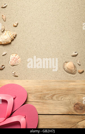 Summer concept with pink flip flops and shells on sandy beach. Top view Stock Photo