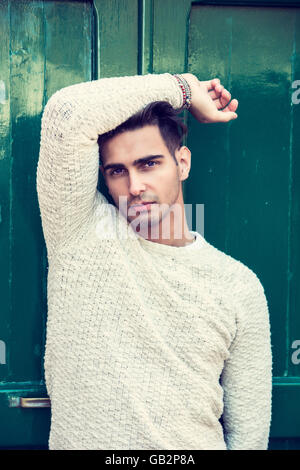 Elegant young man leaning against old wall and green door Stock Photo