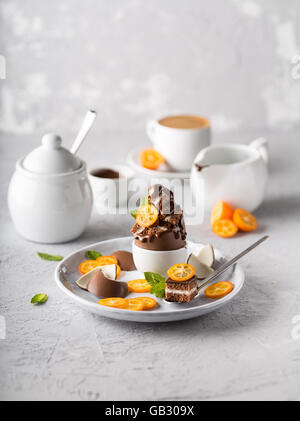 Chocolate dessert with fresh kumquats and a cup of coffee on background Stock Photo