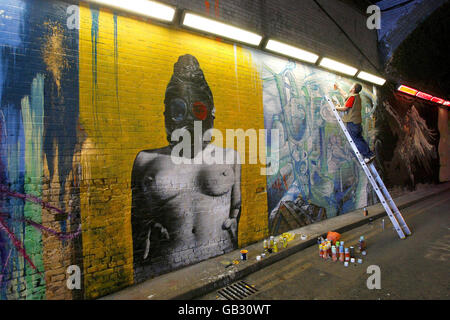 Graffiti artist Chu, from Walsall in the west Midlands, works on a design in a railway tunnel beside Waterloo Station in south London. Stock Photo