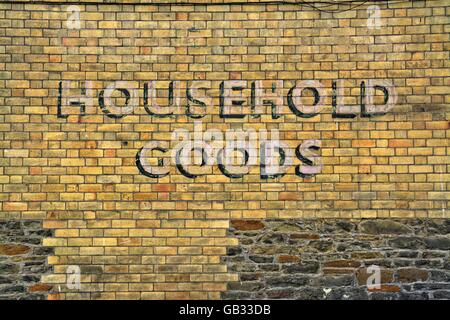 Household Goods - old painted advertisement on red / yellow brick wall Stock Photo