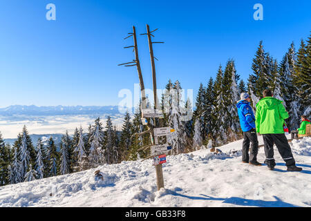 GORCE MOUNTAINS, POLAND - FEB 14, 2015: tourists standing near mountain trail sign near Turbacz shelter. Winter camp takes place Stock Photo