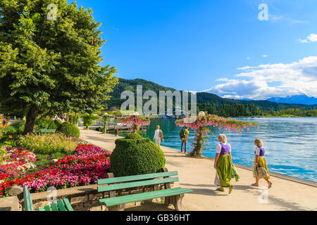WORTHERSEE LAKE, AUSTRIA - JUN 20, 2015: two women wearing traditional clothes walking along Worthersee lake shore during summer Stock Photo