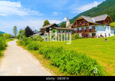 Walking path in small alpine village on shore of Weissensee lake with traditional houses in background, Austria Stock Photo