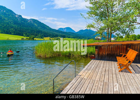 WEISSENSEE LAKE, AUSTRIA - JUL 6, 2015: A man in kayak on water of Weissensee lake in summer landscape of Alps Mountains, Austri Stock Photo