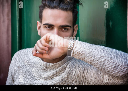 Elegant young man leaning against old wall and green door Stock Photo