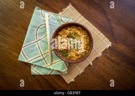 Spicy asian ramen noodle soup with chopsticks in wooden bowl Stock Photo