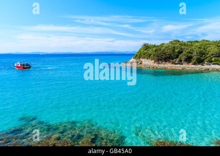 Tourist boat cruising on turquoise sea water near Petit Sperone bay, Corsica island, France Stock Photo