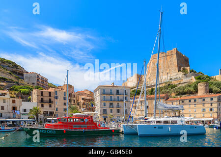 BONIFACIO PORT, CORSICA ISLAND - JUN 25, 2015: catamaran and rescue boat anchoring in Bonifacio port with citadel building in ba Stock Photo