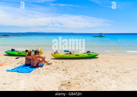 CORSICA ISLAND, FRANCE - JUN 25, 2015: couple of people resting on sand near kayaks Grande Sperone beach, Corsica island, France Stock Photo