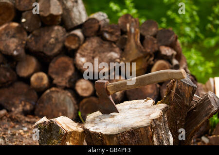 Old ax on log and firewood in the background Stock Photo