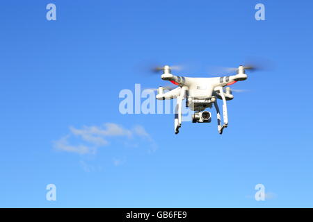 A drone, or UAV, or quadcopter, in flight under a vivid blue sky. Stock Photo