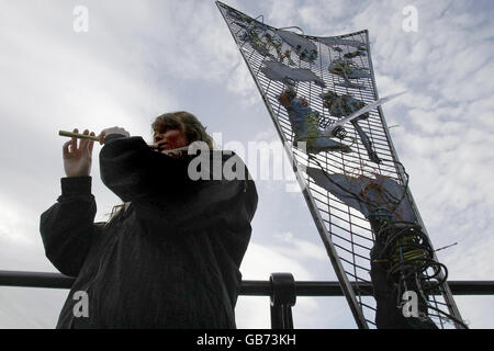 Barbara O'Conner from Bayside plays the tin whistle beside a sculpture made by inmates from Mountjoy prison at a ceremony to unveil a World Poverty commemorative stone near the Famine Memoria in Dublin today. Stock Photo