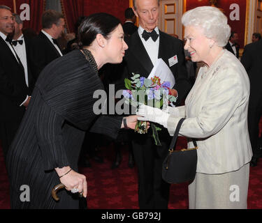 Gill Hicks, a survivor of the London 7/7 bombings, presents Queen Elizabeth II with a posy at St James' Palace in London, at a reception to mark the 60th anniversary of the Leonard Cheshire Disability. Stock Photo