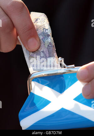 A five pound note is put into a purse with a Saltire (The flag of Scotland) on the side. Forecasters are suggesting the economy is already in recession. Stock Photo