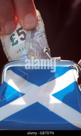 A five pound note is put into a purse with a Saltire (The flag of Scotland) on the side. Forecasters are suggesting the economy is already in recession. Stock Photo