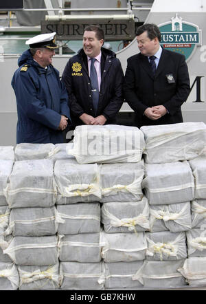 (Left to right) Commander Eugene Ryan from the Irish Naval Service, Superintendent Pat Byrne from the Garda Nation Drugs Unit, and Brian Smyth from Irish Customs with the half a billion euro (403m) of cocaine which was seized from a yacht off the west coast of Ireland, in the harbour at Castletown Bere in Co. Cork. Stock Photo