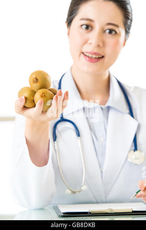 Young asian nutritionist doctor writing diet plan, kiwi Stock Photo