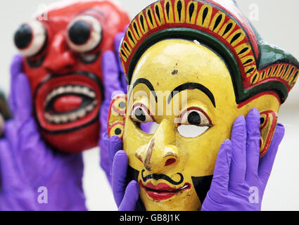 National Museum of Scotland staff members demonstrate 19th Century Sri Lankan performance masks at the press preview of the museum's new exhibition 'Treasured - Wonderful Things, Amazing Stories' which opens in Edinburgh on Friday November 14. Stock Photo