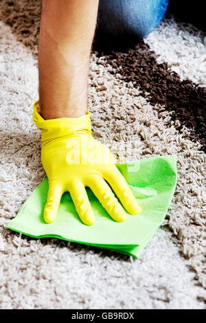 Man in yellow gloves cleaning carpet Stock Photo