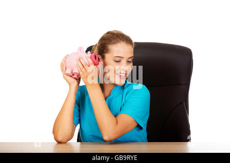 Young female doctor or nurse holding piggybank Stock Photo