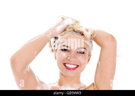 Beautiful smiling young woman washing her hair with shampoo - isolated on white. Stock Photo