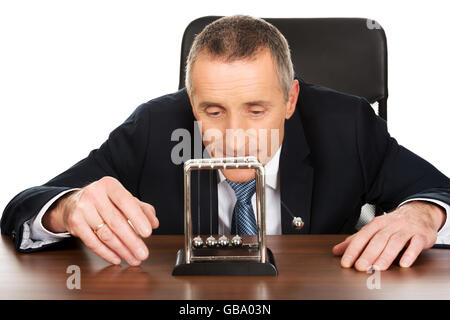Businessman in office playing with newton balls Stock Photo