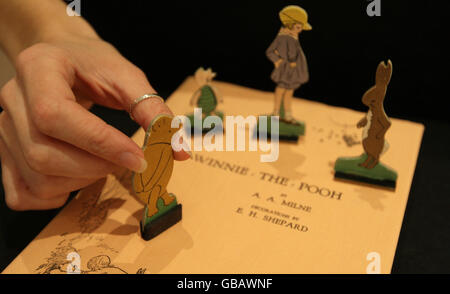 A member of staff at Sotheby's auction house adjusts a display of figures from 'Pooh Goes Visiting' a set of early Winnie the Pooh merchandise, part of a collection of Winnie the Pooh illustrations and books which will be sold at auction on 17th December. Stock Photo