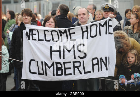 A banner is held up to greet HMS Cumberland as it arrives at Devonport Naval Base in Plymouth after returning from deployment off the Somalia coast. Stock Photo