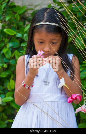 A Salvadoran girl decorates palm fronds with flowers during the Flower & Palm Festival in Panchimalco, El Salvador Stock Photo